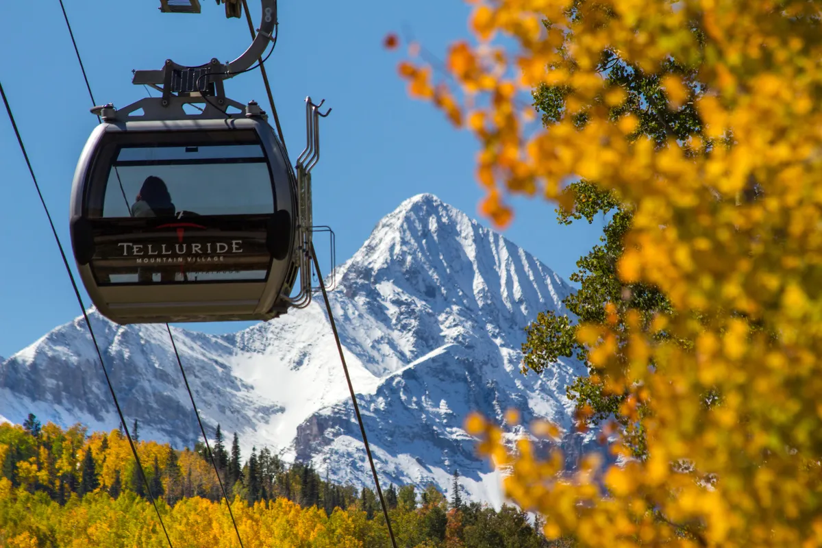This image features a gondola gliding above a snow-capped mountain with colorful autumn foliage below, evoking the thrill and beauty of mountain exploration. The scene offers a sense of adventure and direct connection to the landscape, mirroring the section's mention of easy gondola access for winter and summer activities.