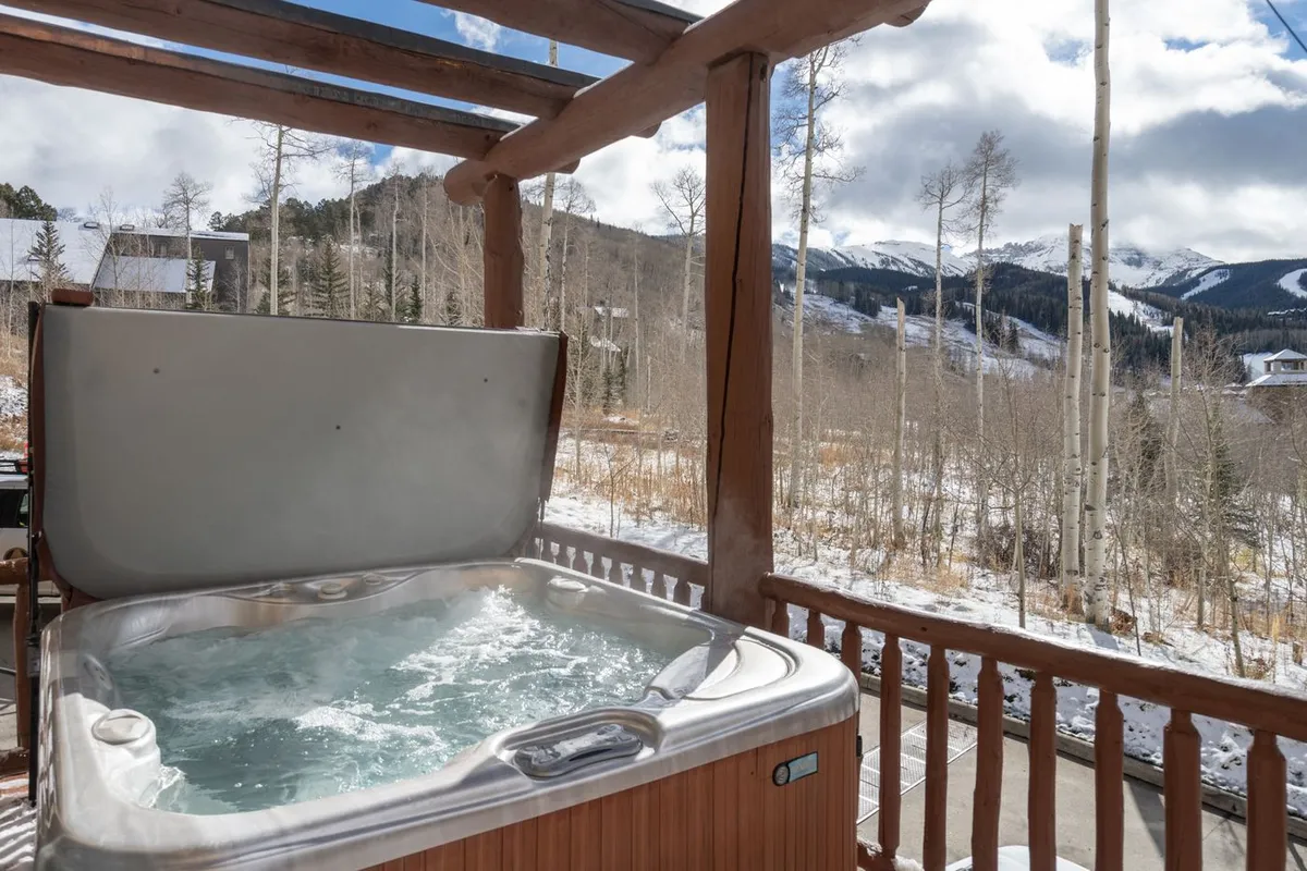 A serene deck features a hot tub with panoramic mountain views, inviting families to relax after a day of exploration. The tranquil setting is perfect for unwinding while staying connected to nature.