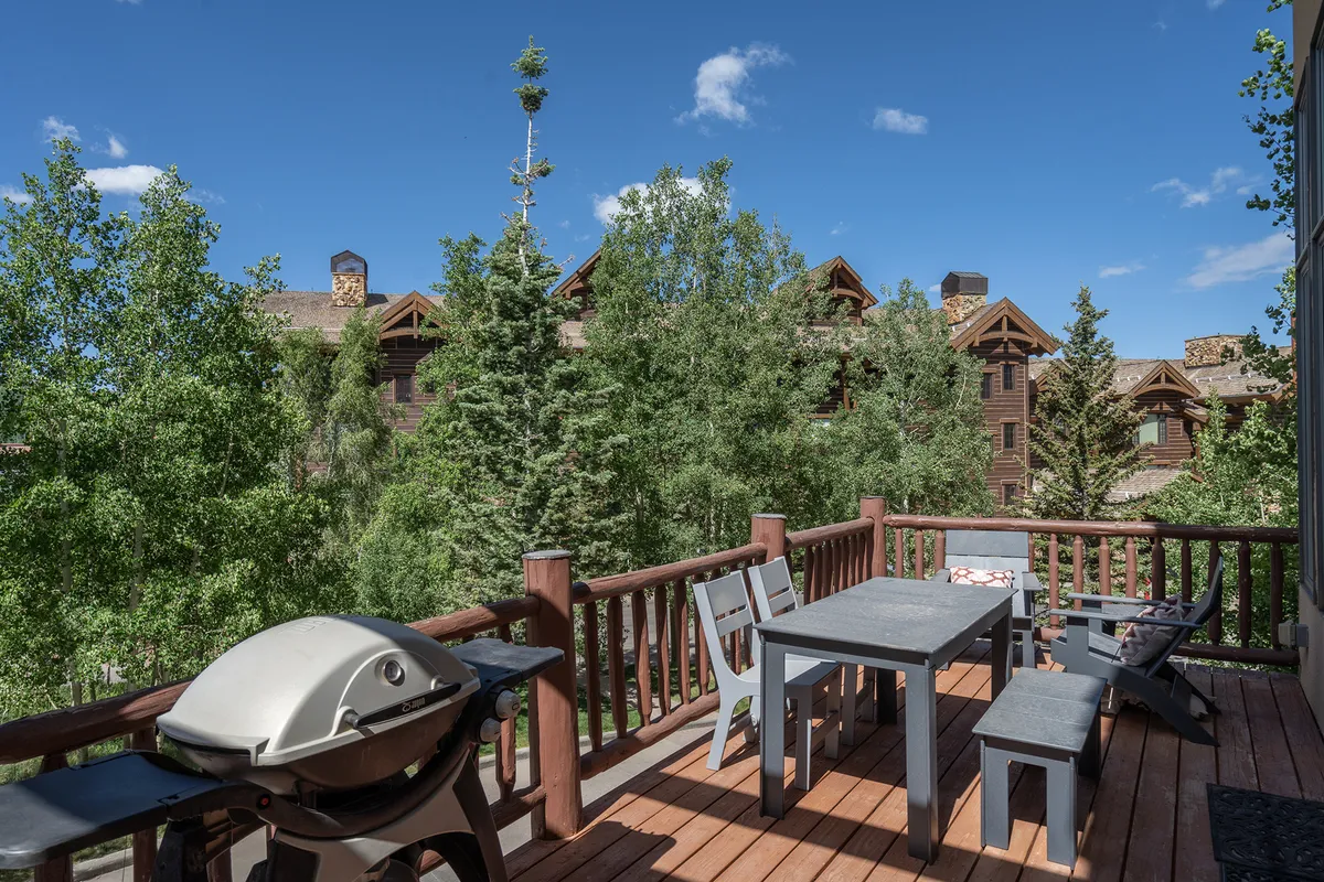 This image features an outdoor dining table and a grill on a deck, surrounded by leafy trees. The setting is perfect for family gatherings, sunset barbecues, or enjoying a morning coffee, connecting directly to the BBQ and outdoor living elements mentioned.